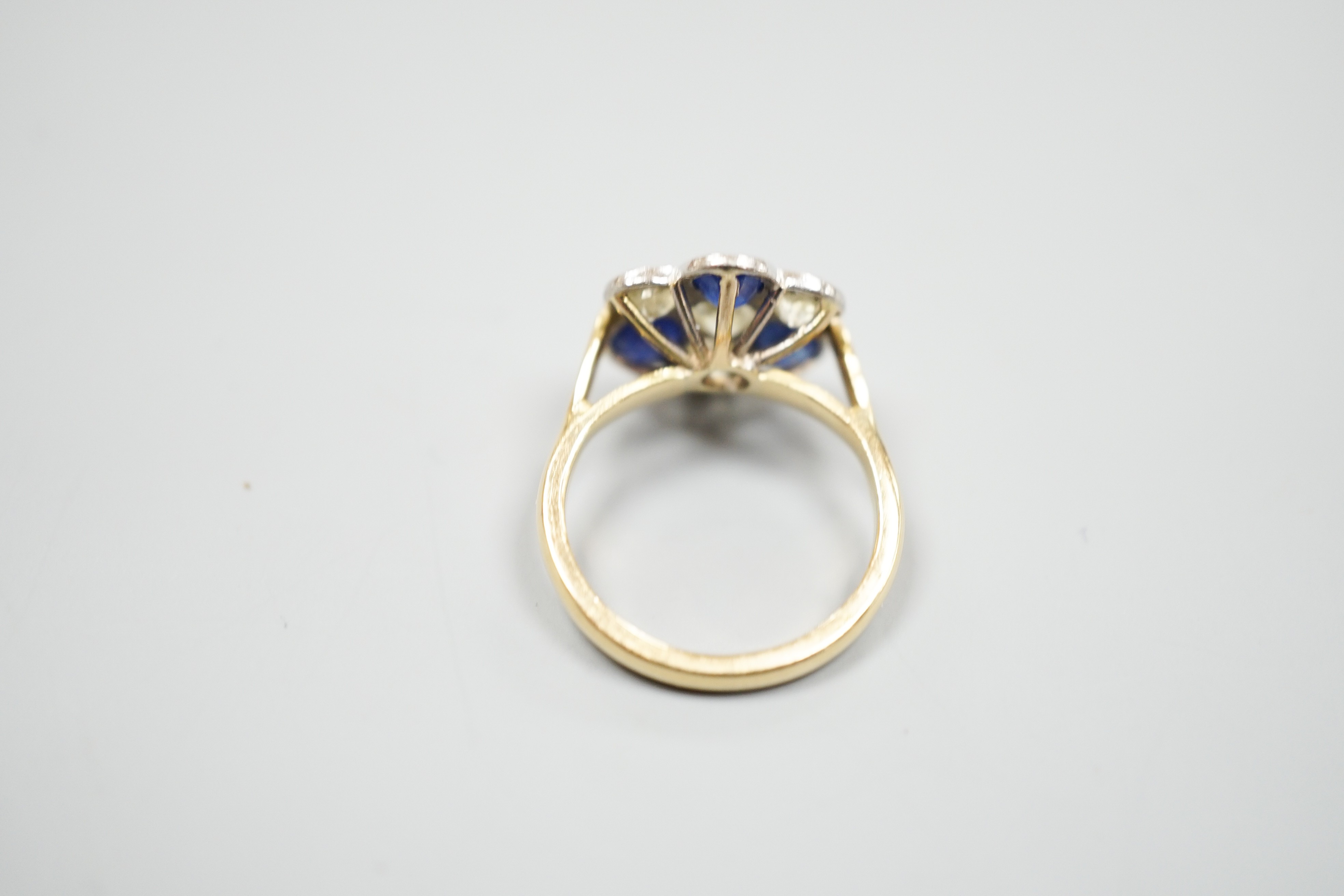 A modern 18ct gold, four stone diamond and three stone sapphire set flower head cluster ring, size J, gross weight 4.1 grams.